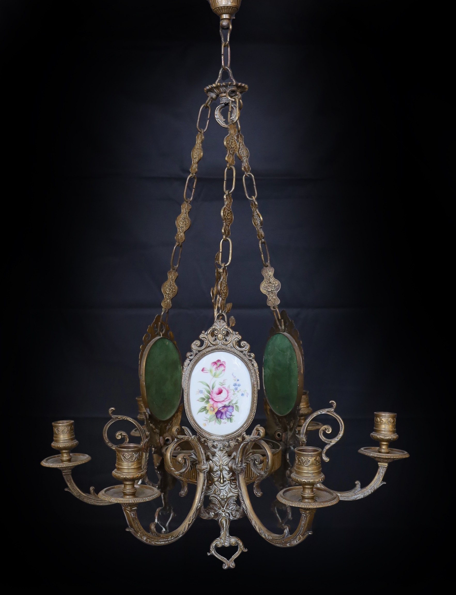 A 1930s English bronze and porcelain six light chandelier with central foliate stem and three oval porcelain plaque decorated with flowers, height 79cm. width 55cm